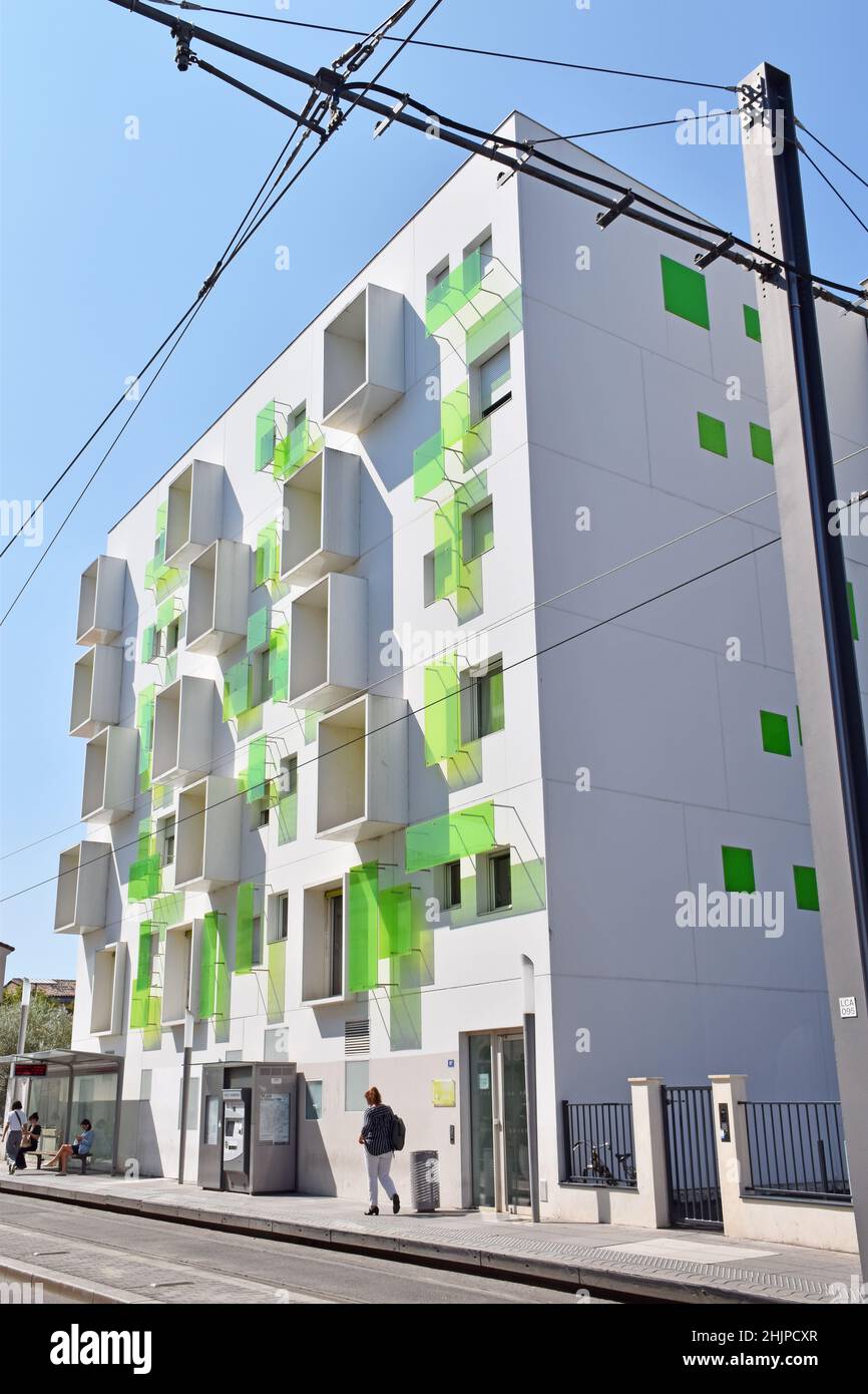 Ein kleiner, moderner weißer, sechsstöckiger Apartmentblock mit hellgrünen Glaspaneelen und vorspringenden Kisten an einigen Fenstern, die die Fassade beleben. Stockfoto