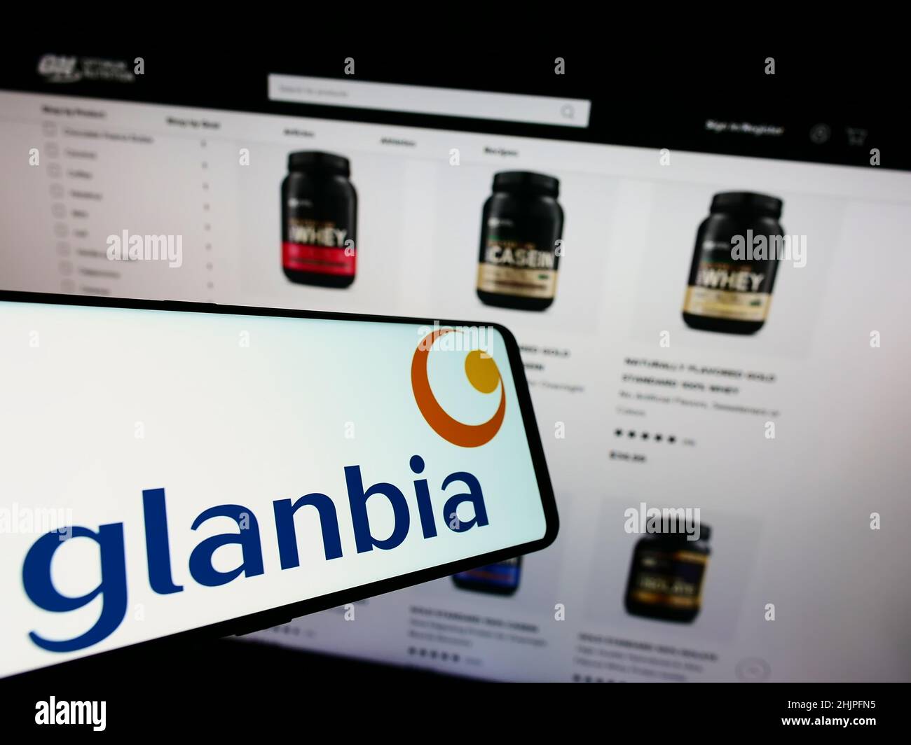 Handy mit Logo des irischen Ernährungsunternehmens Glanbia plc auf dem Bildschirm vor der Business-Website. Fokus rechts neben dem Telefondisplay. Stockfoto