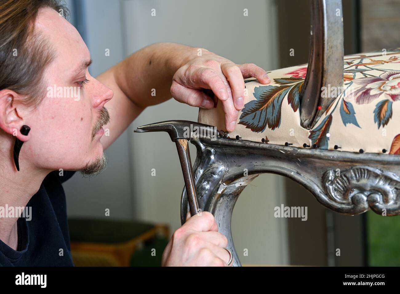 Potsdam, Deutschland. 31st Januar 2022. Der Restaurator Maximilian Busch arbeitet in den Werkstätten der Stiftung Preußische Schlösser und Gärten Berlin-Brandenburg an einem Originalsessel im Stil des Frederikers Rokoko aus der Wohnung von Prinz Heinrich im Neuen Schloss aus der Mitte des 18th. Jahrhunderts. Die Polsterung wurde in echtem Stil mit den Techniken der Zeit mit dem Füllstoff Rosshaar hergestellt und mit bedrucktem Leinen bedeckt. Die Rückenlehne ist noch original. Der Sessel aus Lindenholz wird bald wieder bewundert. Quelle: Jens Kalaene/dpa-Zentralbild/ZB/dpa/Alamy Live News Stockfoto