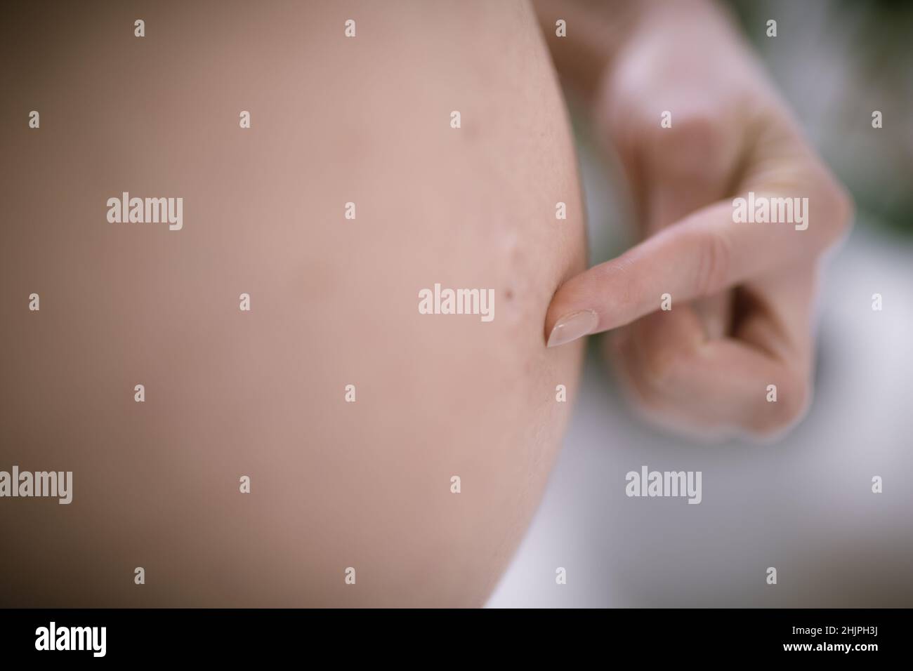 Schwanger Frau Bauch. Schwangerschaftskonzept. Isoliert auf schwarzem Hintergrund. Schwanger Bauch Nahaufnahme mit Finger zeigt auf Bauchnabel. Stockfoto