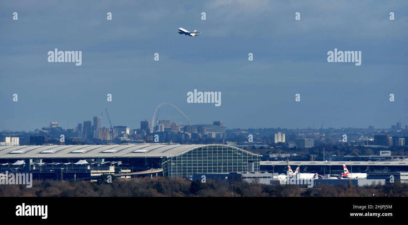 Ein Flugzeug verlässt den Londoner Flughafen Heathrow und klettert über Terminal 5 mit dem Wembley Arch im Hintergrund Stockfoto