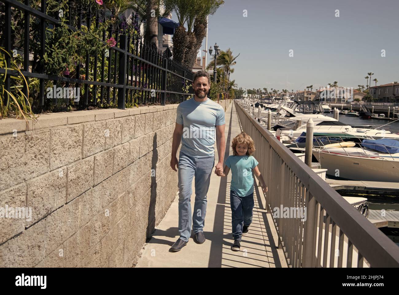 Gemeinsam spazieren gehen. Vater und Sohn gehen mit Händen auf die Promenade. Mann und Kind genießen gemächlichen Spaziergang Stockfoto