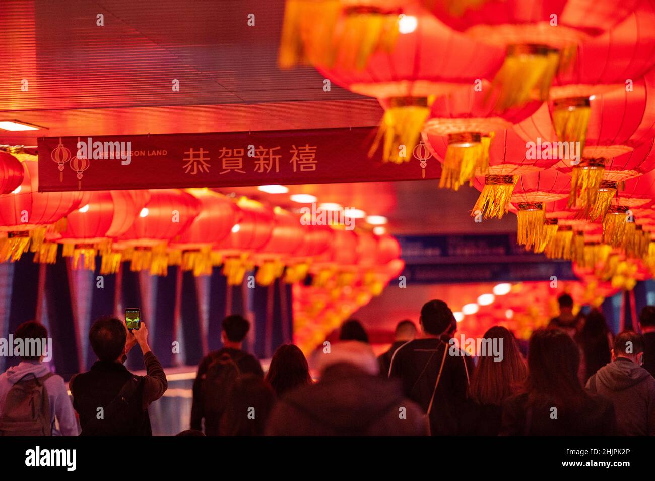 Hongkong, China. 28th Januar 2022. Die Menschen gehen durch eine Fußgängerbrücke, die mit roten Laternen für das bevorstehende chinesische Mondjahr des Tigers in Hongkong geschmückt ist. (Foto von Miguel Candela/SOPA Images/Sipa USA) Quelle: SIPA USA/Alamy Live News Stockfoto