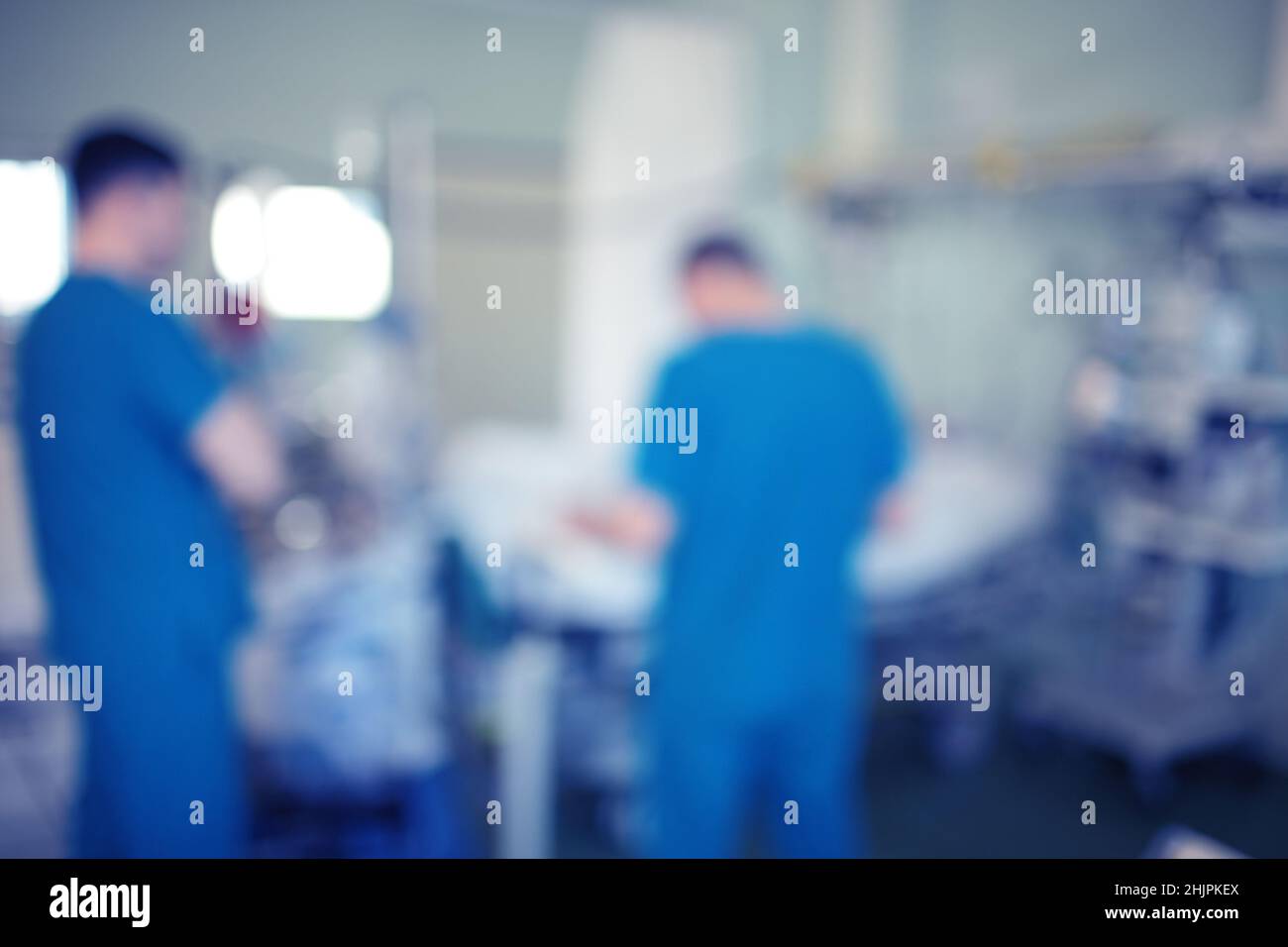 Verschwommene Sihouetten männlicher Ärzte, die den kritischen Patienten auf der Intensivstation konsultieren, unfokussierter Hintergrund. Stockfoto