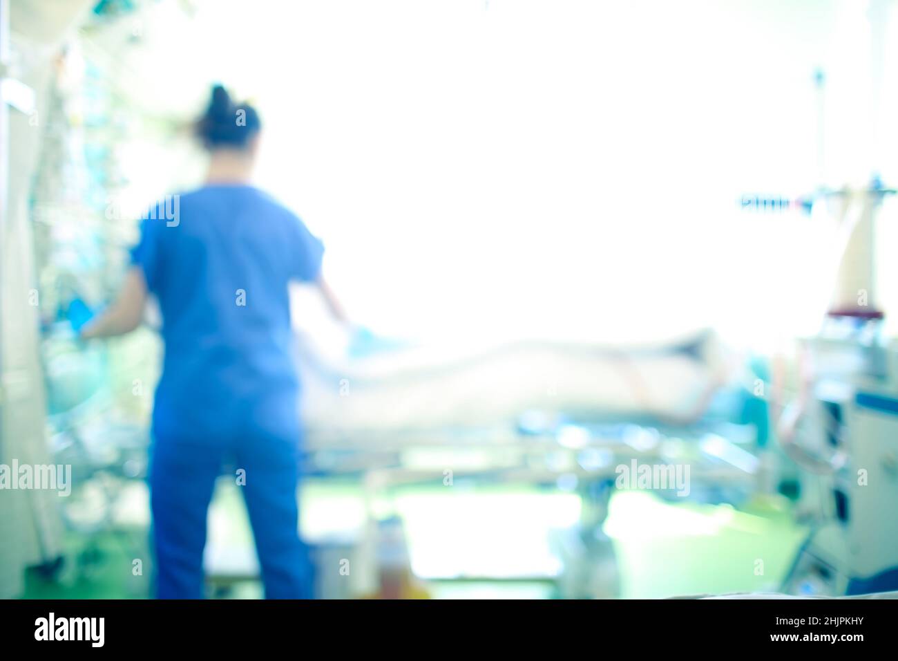 Medizinische Mitarbeiterin am Patientenbett auf der Intensivstation, unfokussierter Hintergrund. Stockfoto