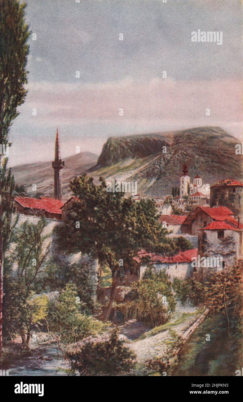 Bleistiftminarette und die edle griechische Kathedrale am Fuße des grimmigen Hügels von Podvelez sind herausragende Merkmale von Mostar. Bosnien Und Herzegowina (1923) Stockfoto