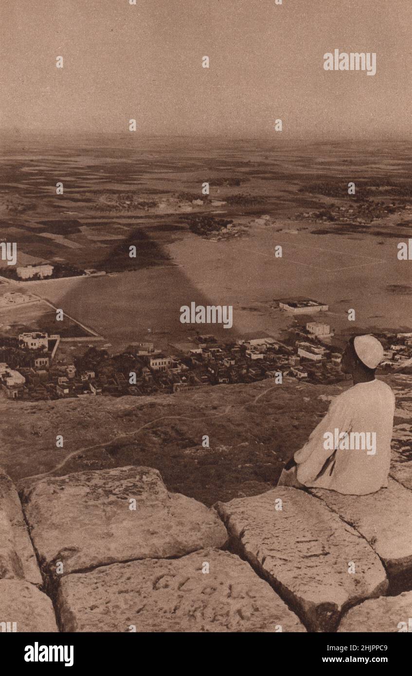 Wie der Gnomon einer gigantischer Sonnenuhr bewegt sich der dreieckige Schatten der Großen Cheops-Pyramide über die fruchtbare Ebene. Ägypten. Kairo (1923) Stockfoto