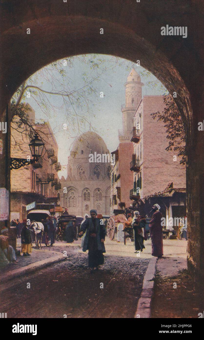 Der Verkehr ist dicht in den Straßen in der Nähe der alten Universität Mahomedan, der Moschee El Azhar, die hier in einem Torbogen eingerahmt ist. Ägypten. Kairo (1923) Stockfoto