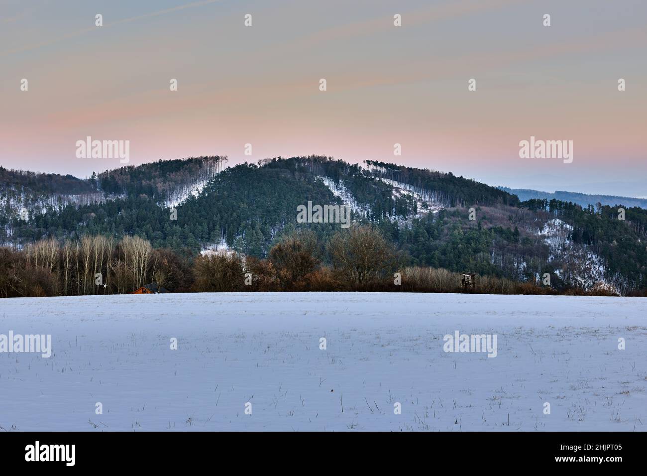 Berglandschaft im Winter mit Hügeln und Nadelbäumen in der Abenddämmerung. Kurz nach Sonnenuntergang. Farbenfroher Himmel. Mit hohem Standfuß. Vrsatec, Slowakei. Stockfoto