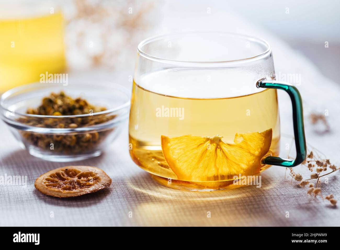 Tasse Kamillentee in transparentem Becher serviert mit einer Scheibe Zitrone und Orange. Teepause. Stockfoto