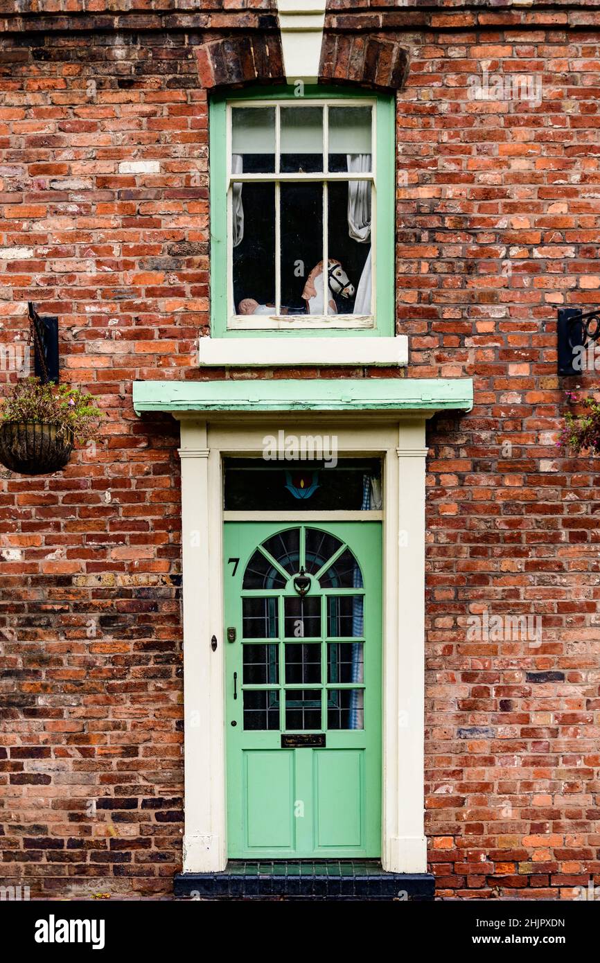 Tür und Fenster darüber, grün gestrichen, in einem roten Backsteinhaus in Shropshire, West Midlands Stockfoto