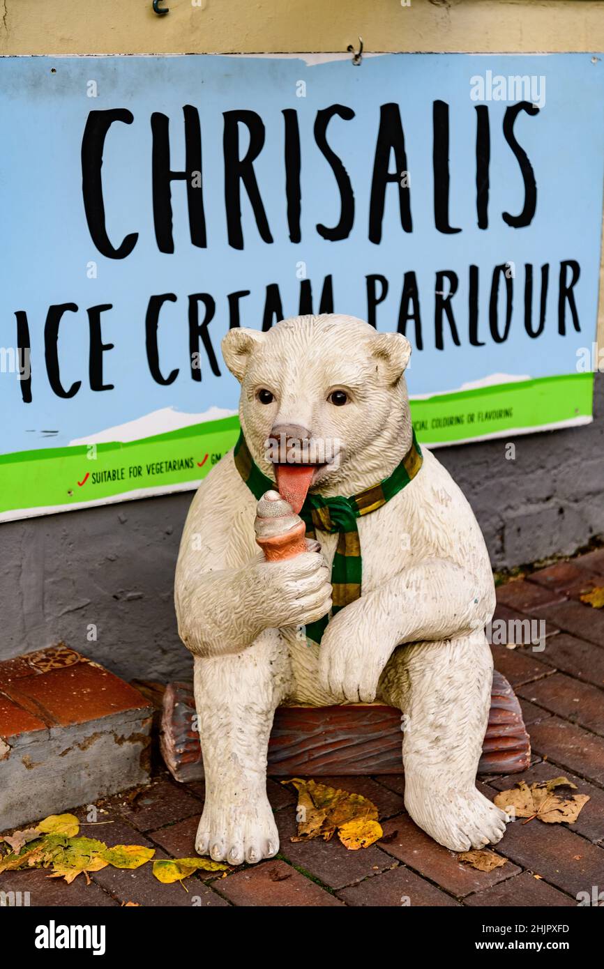 Modell eines Hundes, der Eis vor einer Eisdiele isst, sitzend und gekleidet, als wäre es ein Mensch Stockfoto