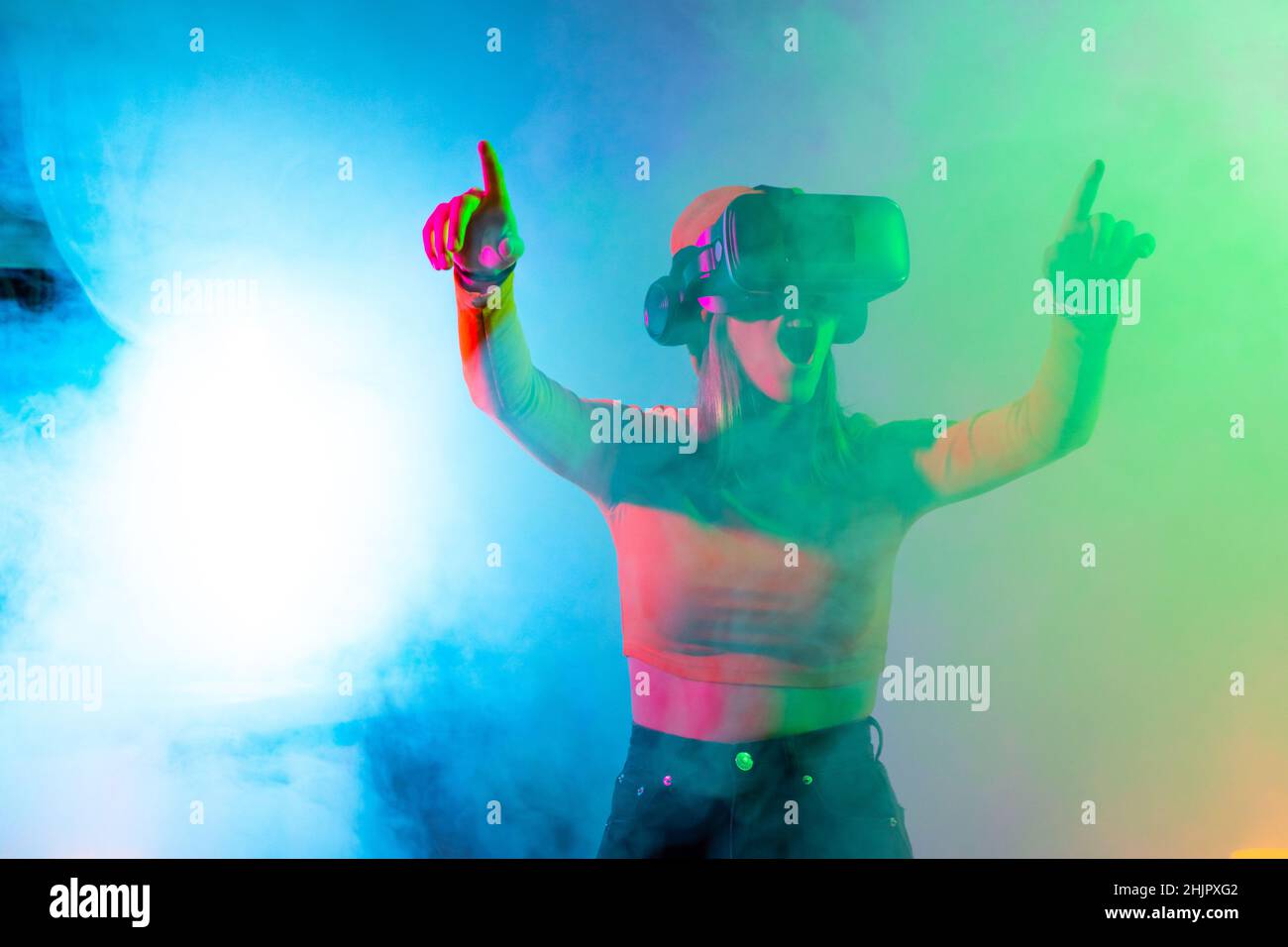 Junge Frau mit Virtual-Reality-Brille im dunklen Raum mit Neonbeleuchtung. Wireless-Technologien. Stockfoto