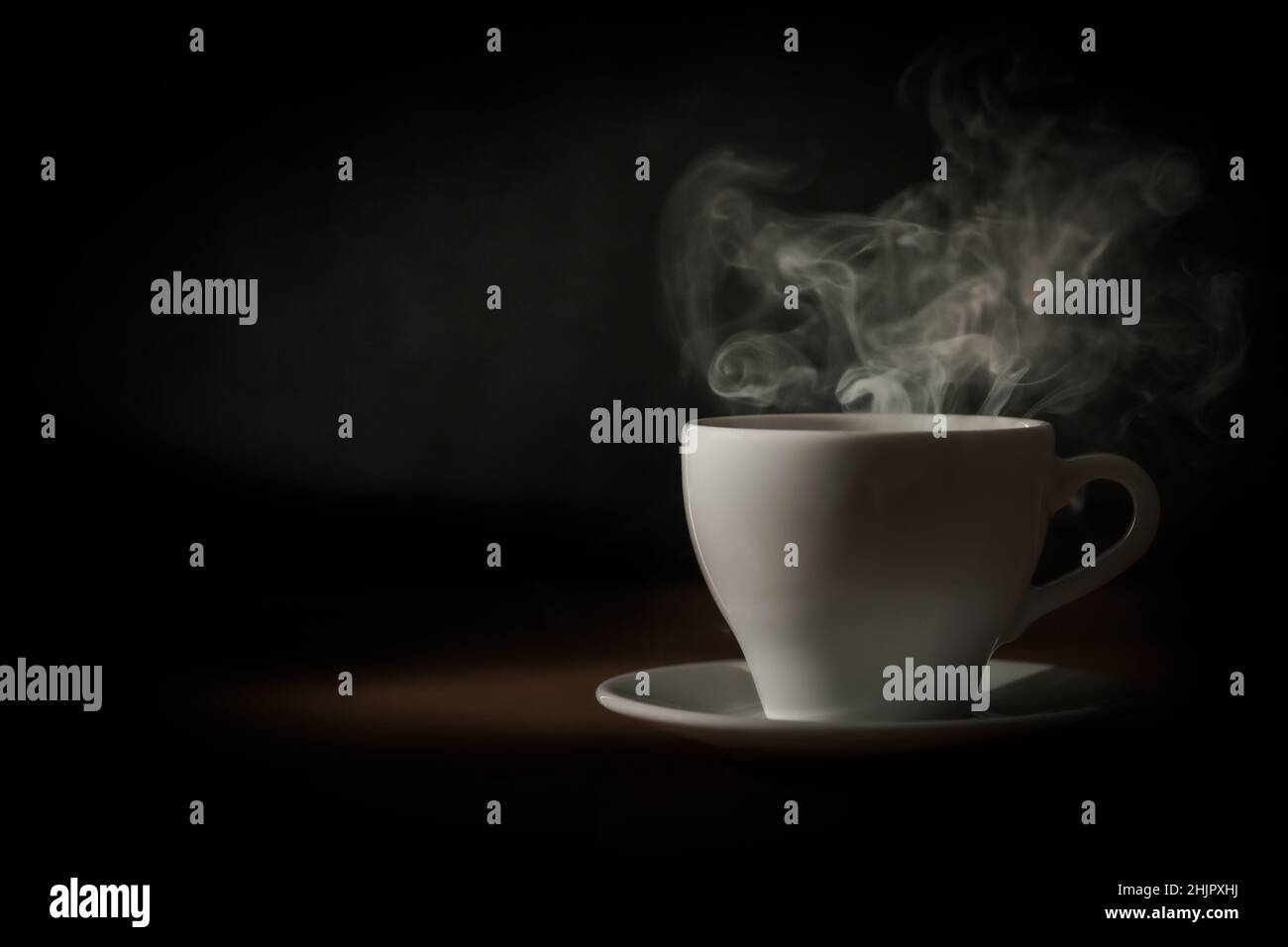 Vor dunklem Hintergrund tritt Dampf aus der Teetasse aus. Stockfoto