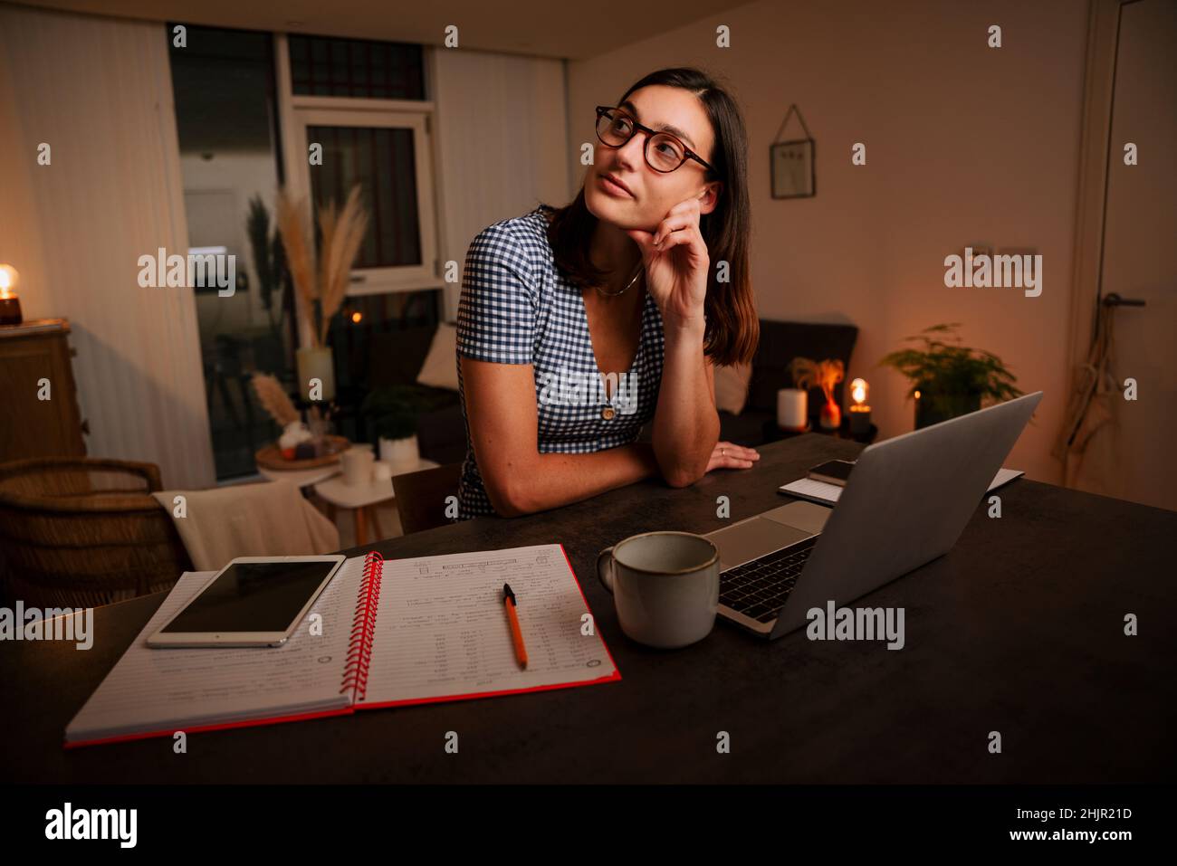 Kaukasischer weiblicher Teenager, der von zu Hause aus träumt, während er in der Küche studiert Stockfoto