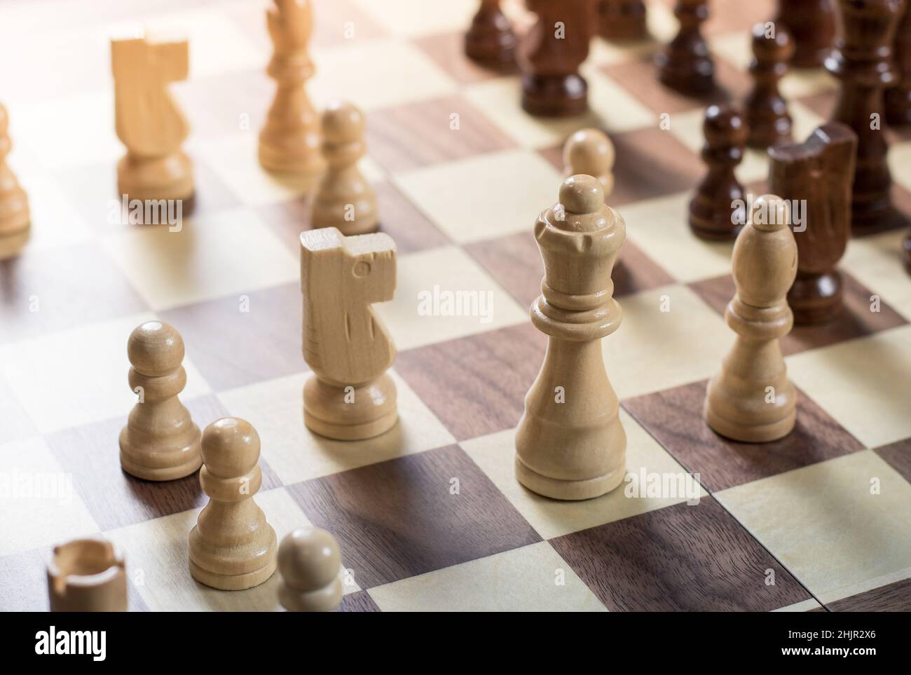 Schachbrett mit Schachspiel wird gespielt. Von oben nach unten. White's Queen und Knight im Fokus Stockfoto
