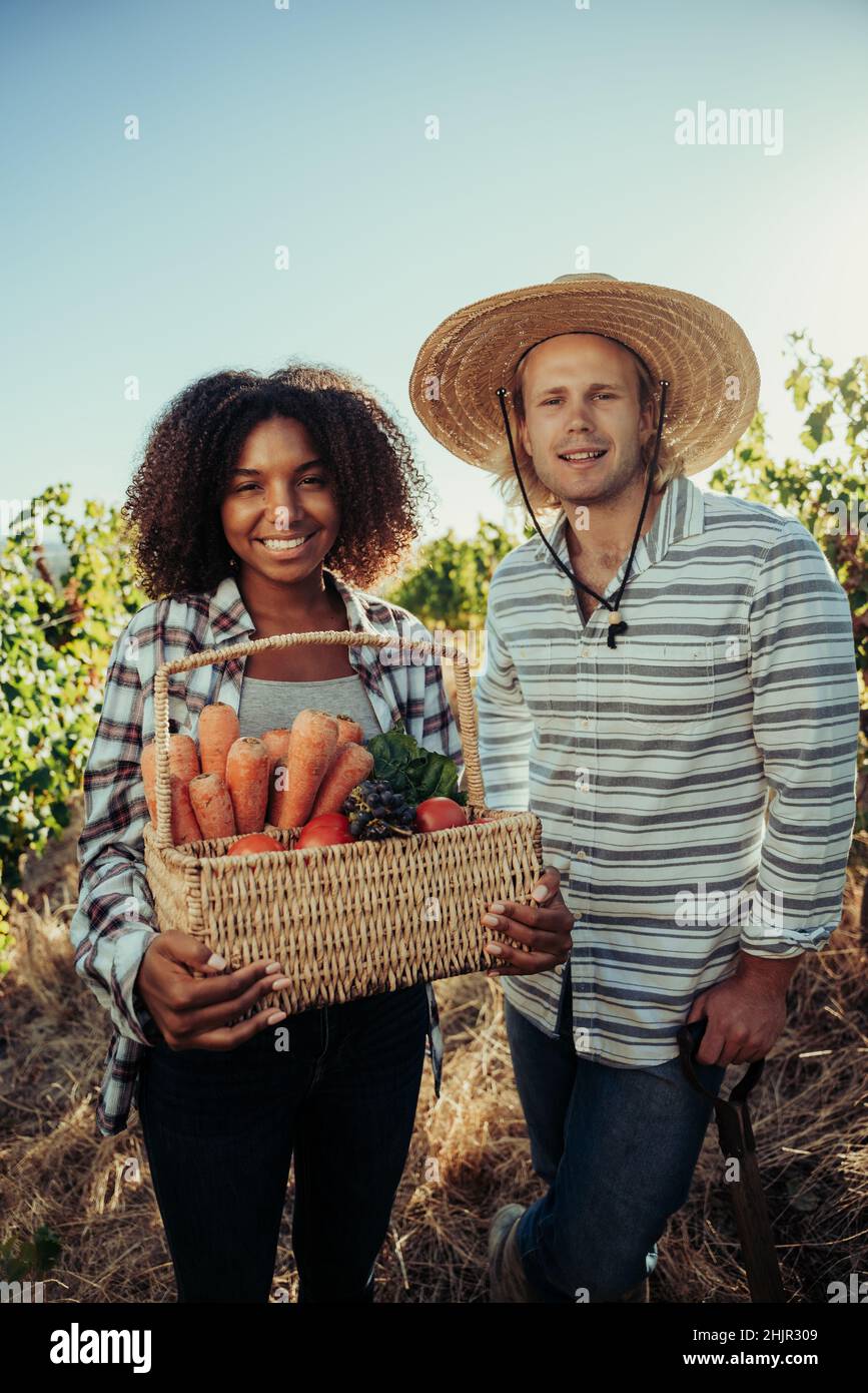 Männliche und weibliche Partner lächeln nach einem erfolgreichen Tag der Gemüseernte auf üppigen Bauernhöfen Stockfoto