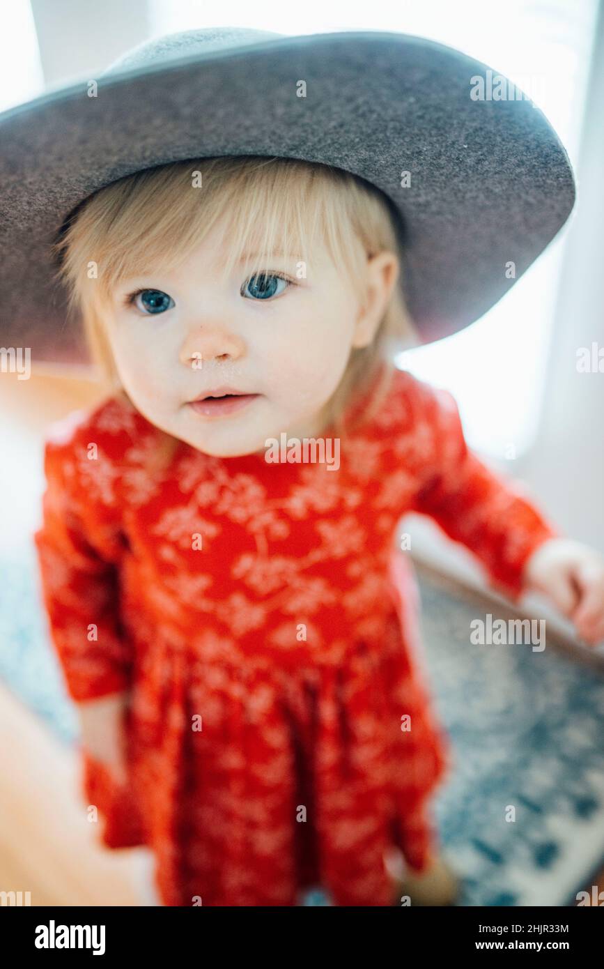 Blauäugiges Mädchen mit grauem Hut und rotem Weihnachtskleid und schmutziger Nase Stockfoto