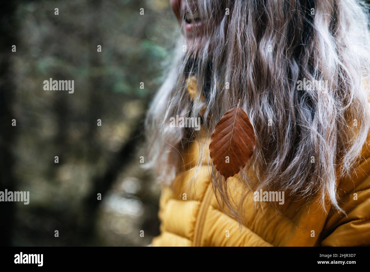 Glückliches Mädchen mit Herbstblättern in ihren blonden Haaren Stockfoto