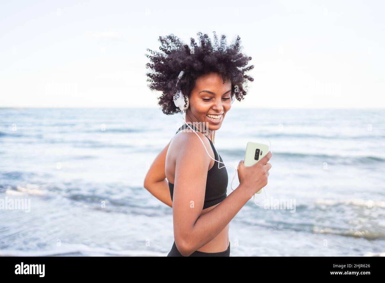 Schwarze Frau lacht und tanzt am Strand Stockfoto