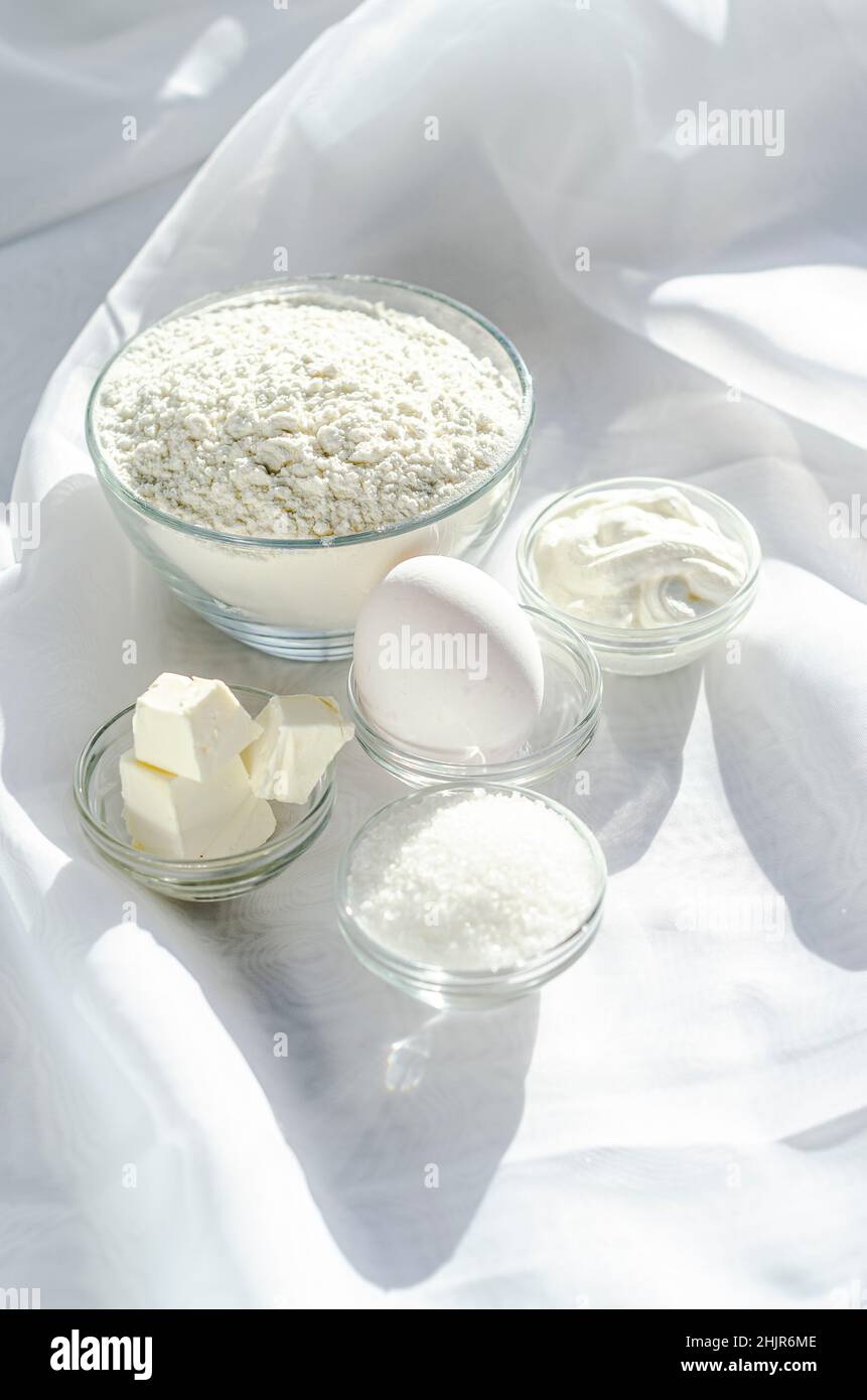 Mehl Zucker saure Creme und Butter in Schüsseln auf weißem Hintergrund Stockfoto