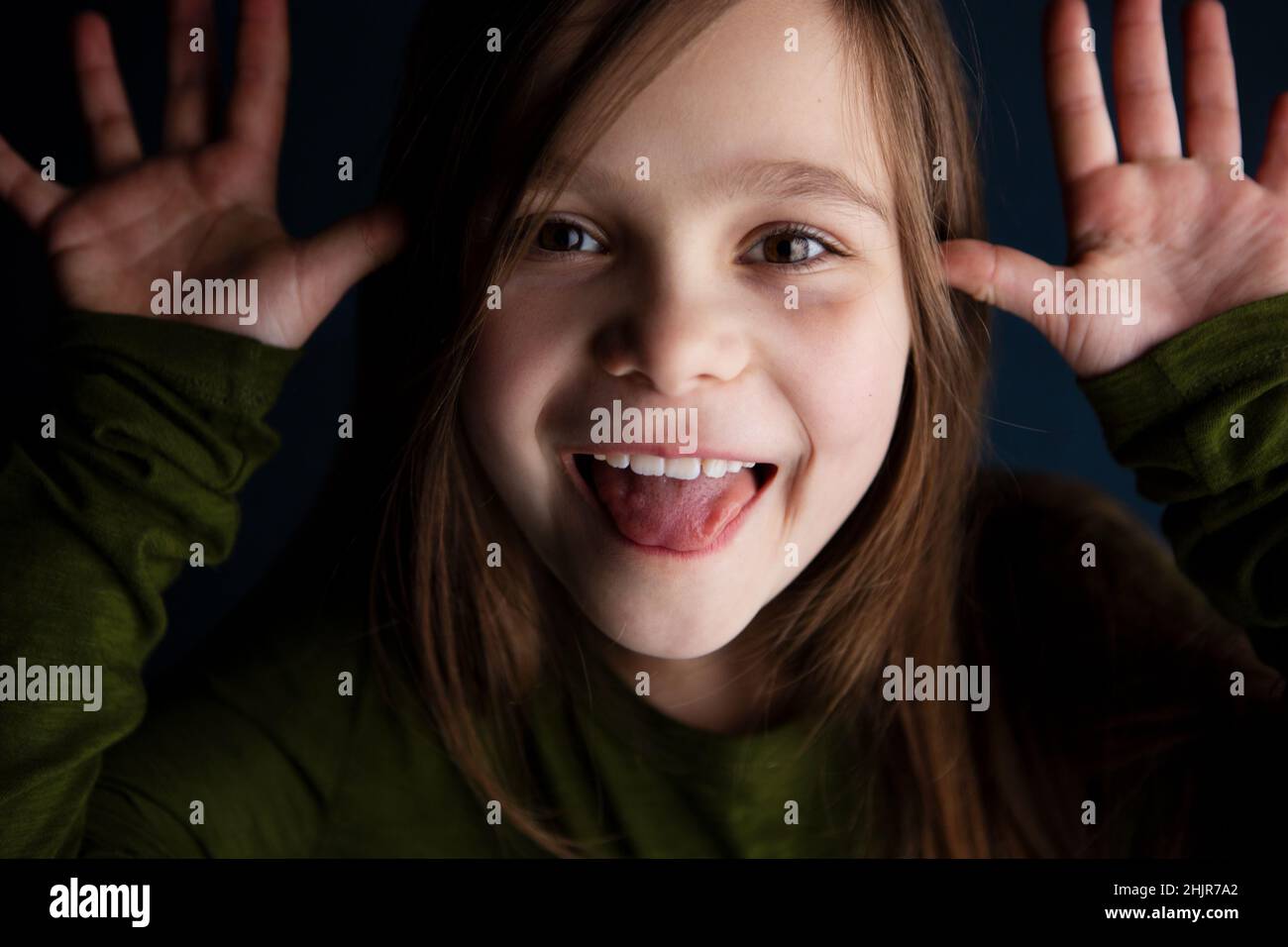 Nettes lächelndes kleines 9-jähriges Mädchen, das ihre Zunge zeigt Stockfoto