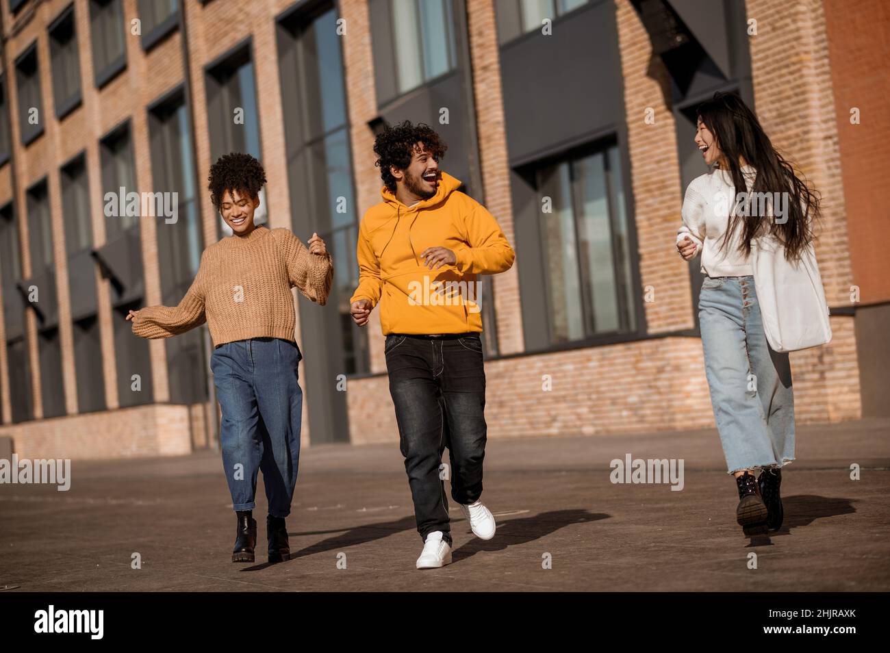 Zwei Mädchen und ein Mann, die in der Nähe des Gebäudes auf der Straße tanzen Stockfoto