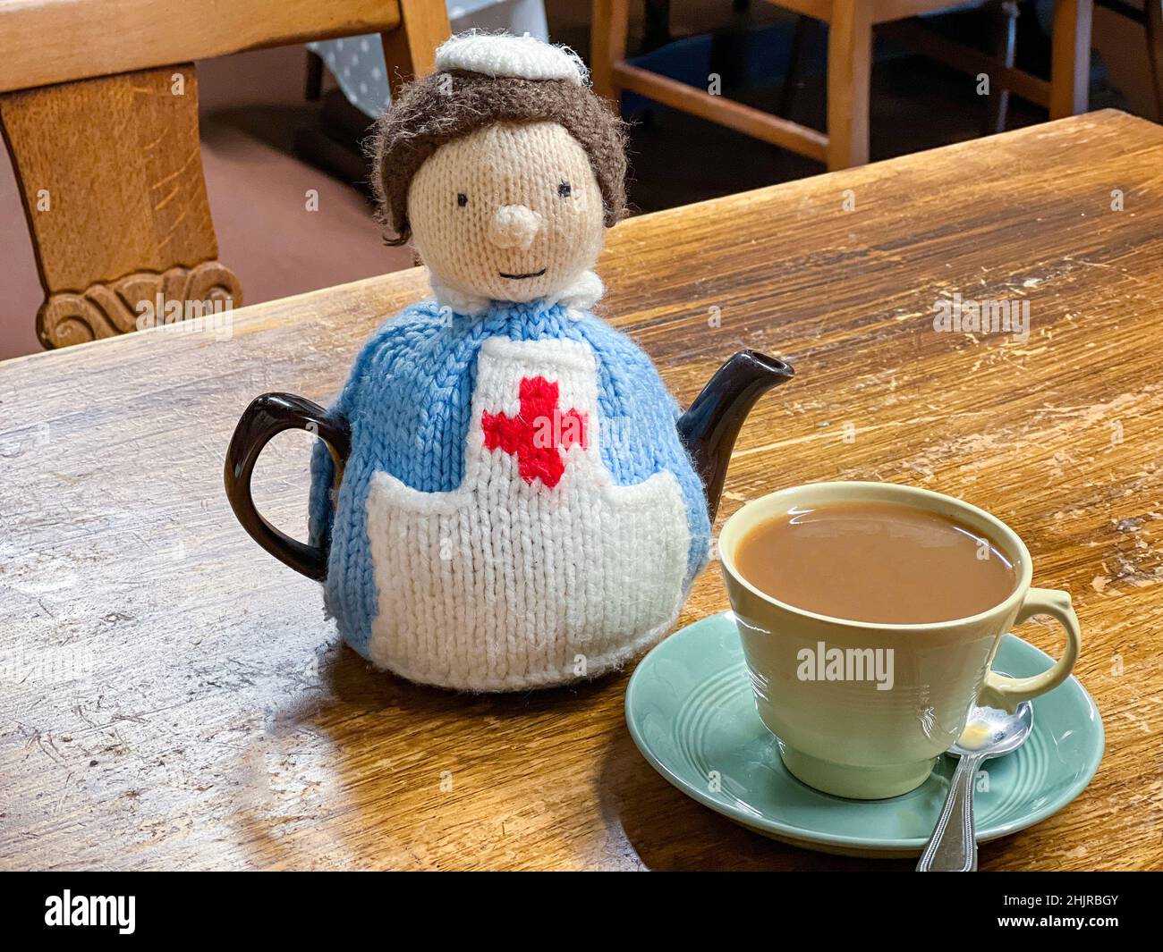 Ein gestrickter Krankenschwester-Tee aus Wolle, gemütlich mit einer heißen Tasse Tee Stockfoto