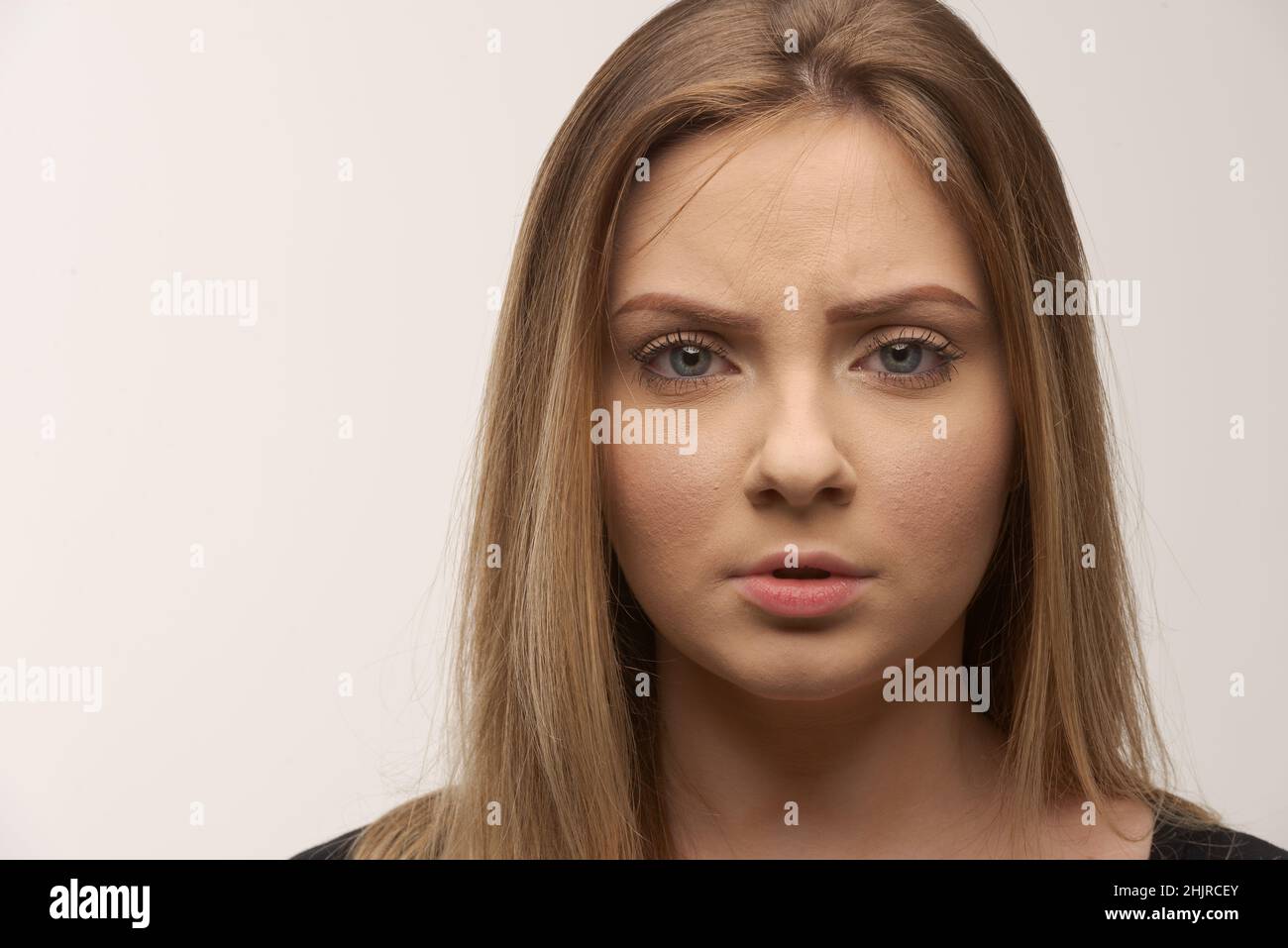 Porträt der traurigen jungen Frau emotional allein auf weißem Hintergrund Stockfoto