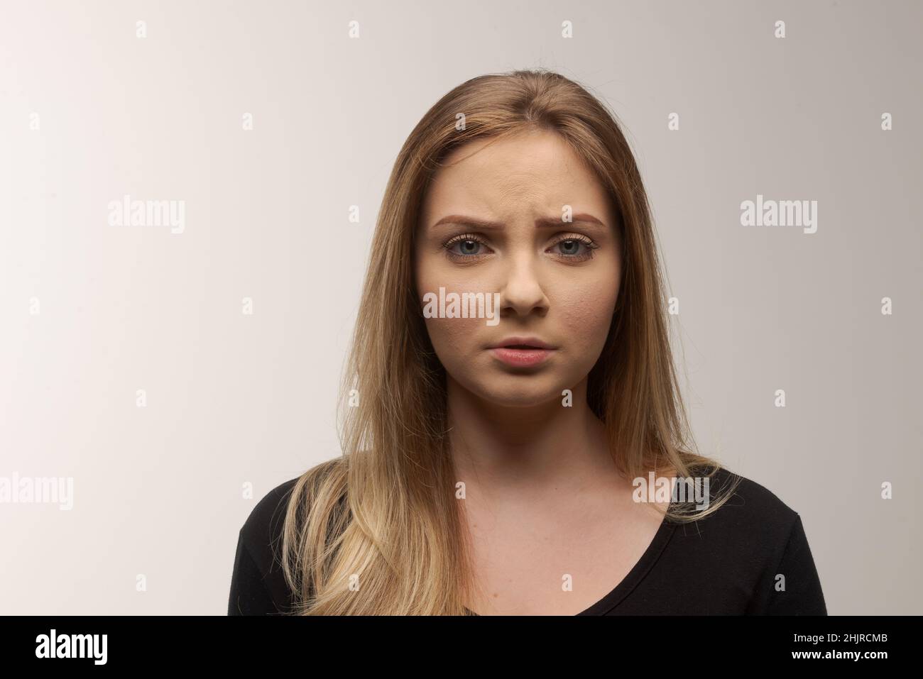 Porträt der traurigen jungen Frau emotional allein auf weißem Hintergrund Stockfoto