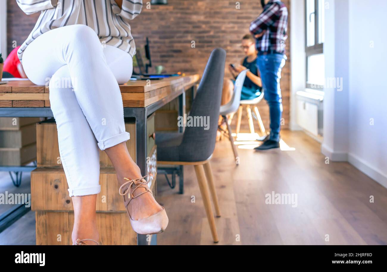 Eine nicht erkennbare Geschäftsfrau, die im Büro auf dem Tisch sitzt Stockfoto