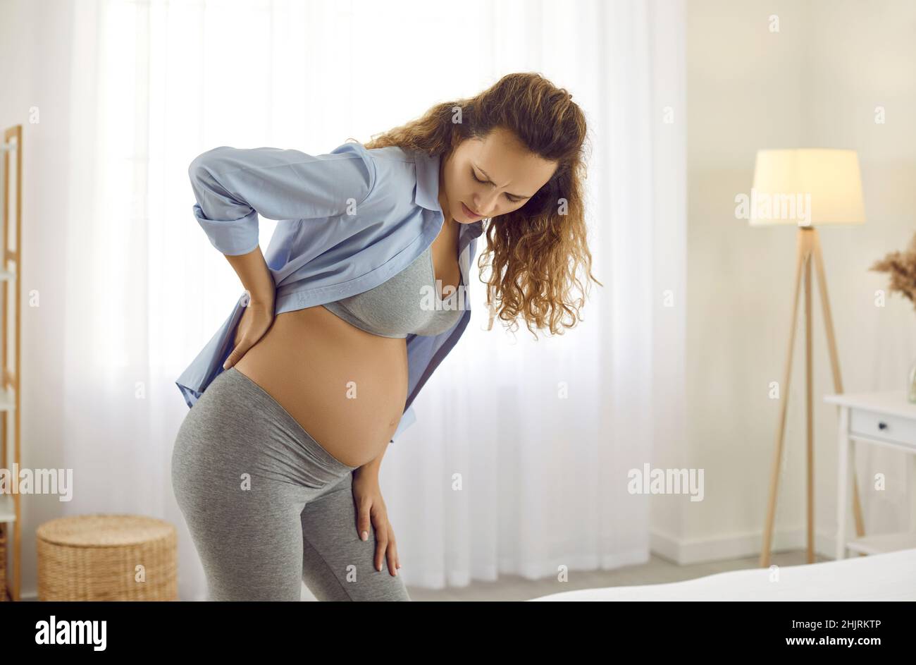 Junge zukünftige Mutter, die während der Schwangerschaft an Schmerzen in ihrem müden unteren Rücken leidet Stockfoto