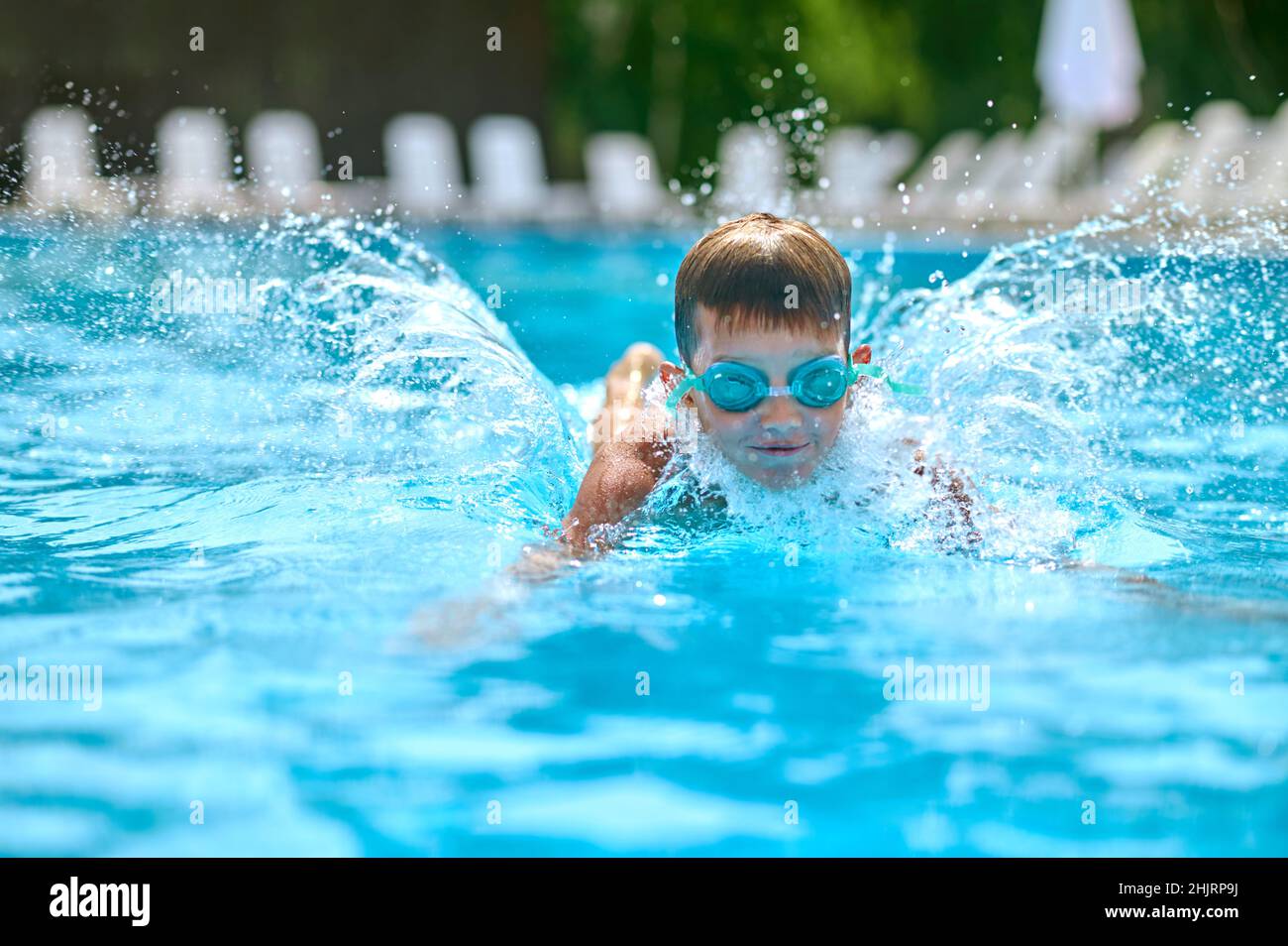 Junge in Schutzbrillen schwimmen plantschen im Pool Stockfoto