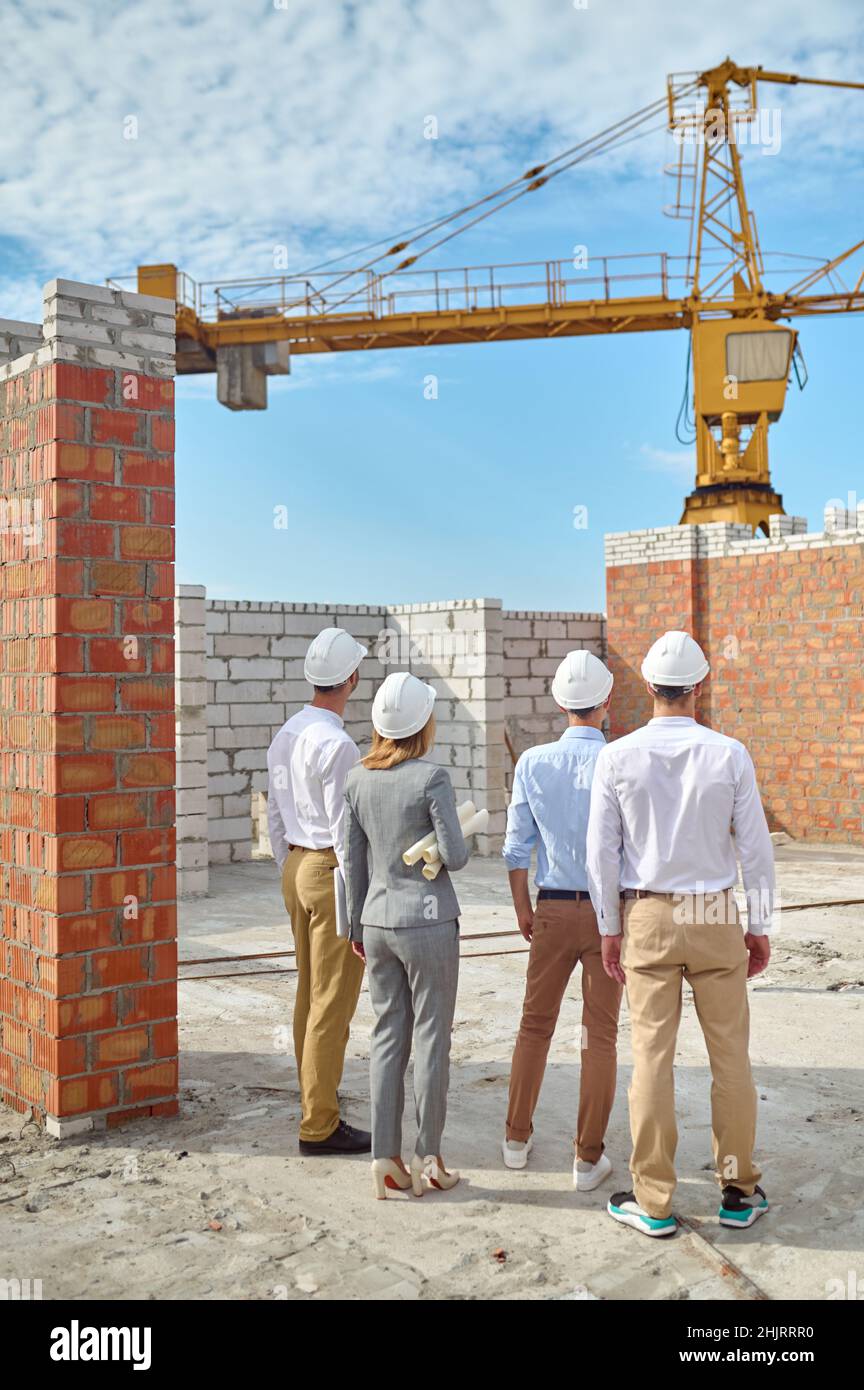 Vier Personen in Schutzhelmen, die den Gebäudebereich inspizieren Stockfoto