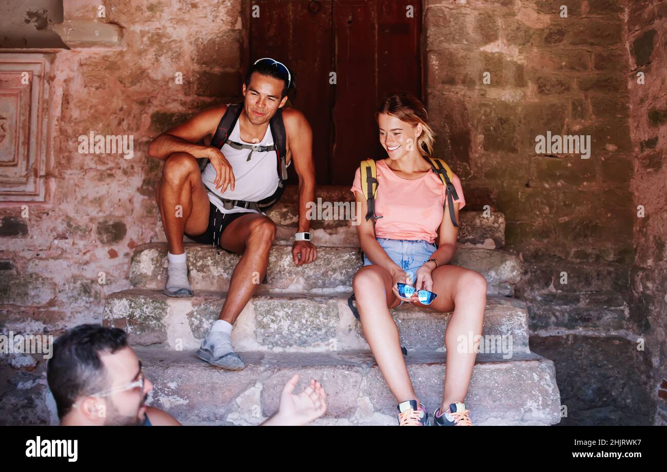 Lächelnde Reisende Freunde unterhalten sich auf einer alten Steintreppe Stockfoto