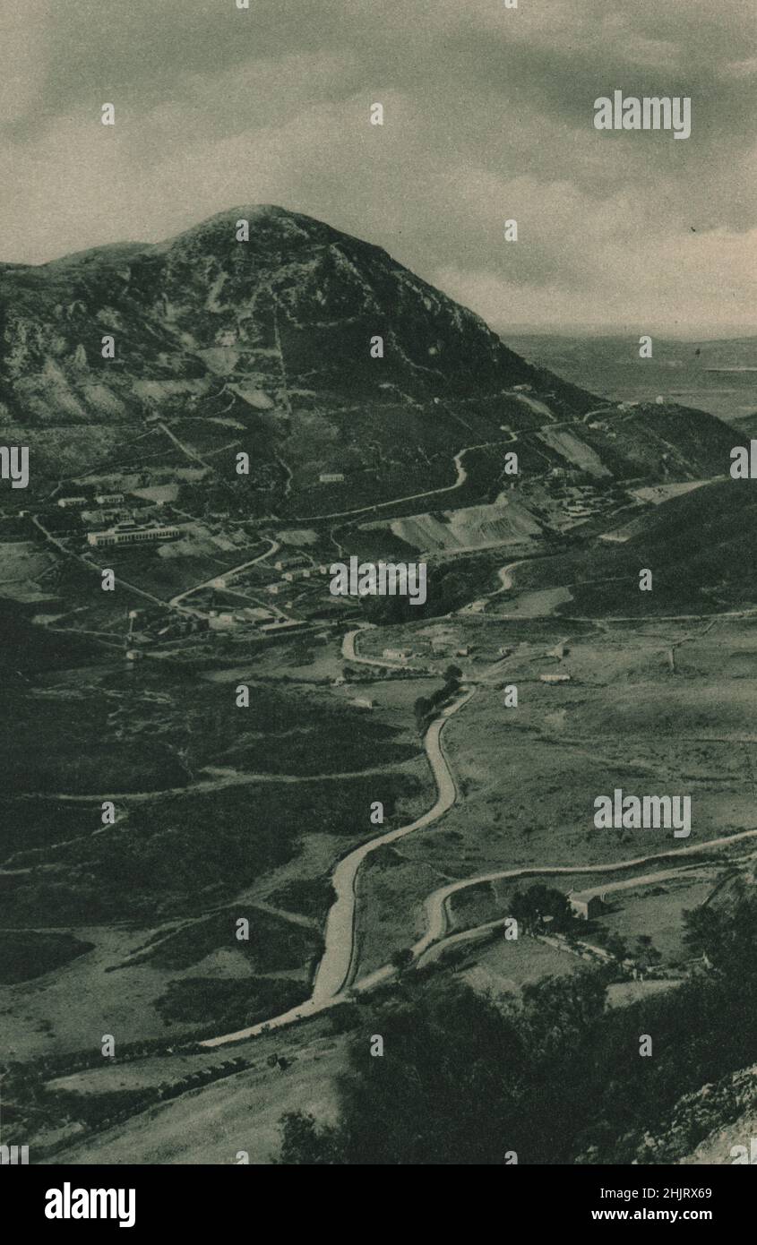 Über das Tal unterhalb von Monteponi befinden sich einige Minenanlagen und eine Straße, die sich über eine Schulter des Hügels nach Gonnesa schlängelt. Italien. Sardinien (1923) Stockfoto