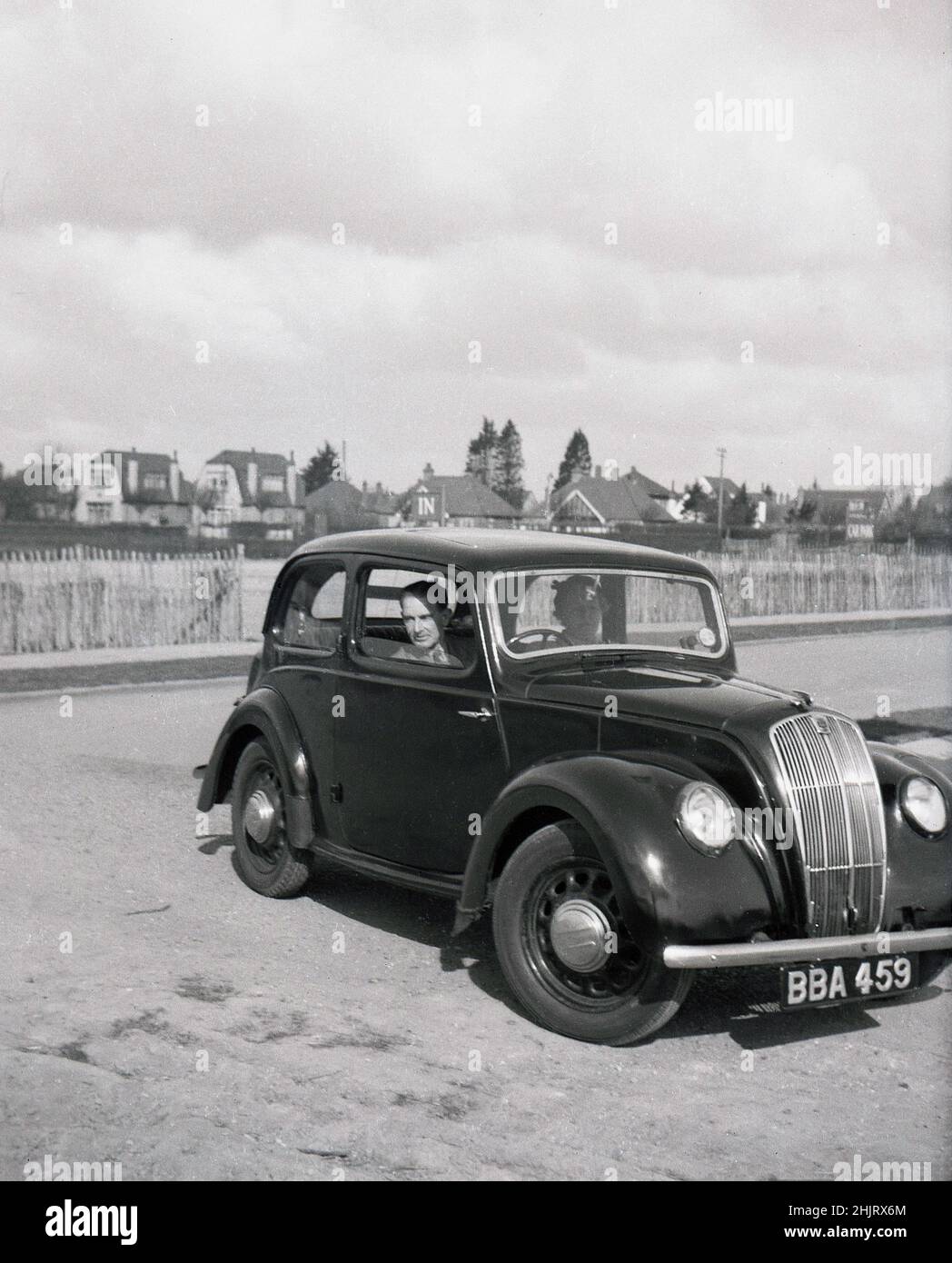 1950, historisches, reifes Paar im Auto der Ära, möglicherweise ein britischer Ford, geparkt an der Küste, England, Großbritannien. In dieser Zeit mit wenig Verkehr und ohne Parkbeschränkungen war es eine beliebte Zeit, mit dem Auto zu fahren. Stockfoto