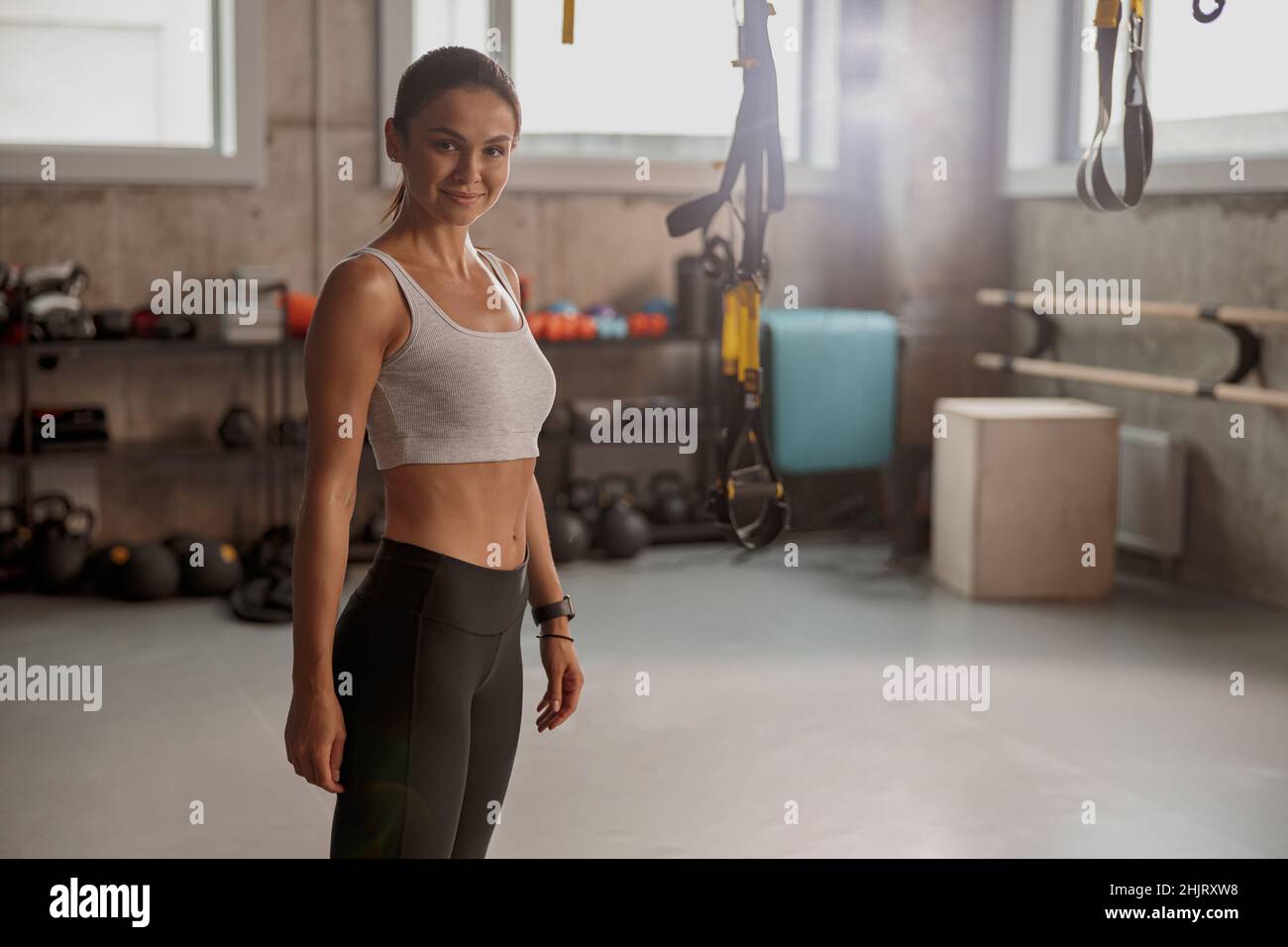 Junge athletische Frau im Fitnessclub lächelt und schaut auf die Kamera Stockfoto