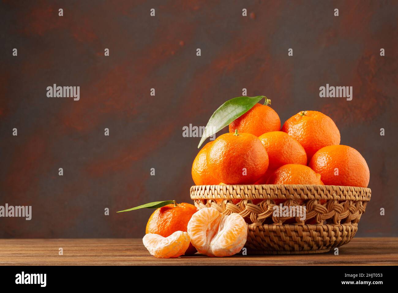 Сlementine Mandarinen mit Blättern in einem Holzkorb auf dunklem Hintergrund mit Kopierraum Stockfoto