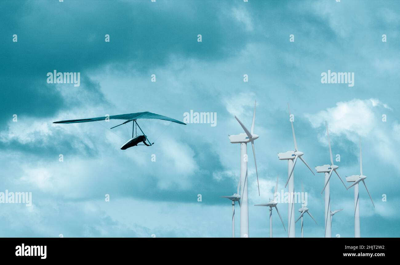 Hängegleiter fliegen über Windenergieanlagen. Saubere, erneuerbare Energie, Netto-Null, Klimawandel, globale Erwärmung... Konzept Stockfoto