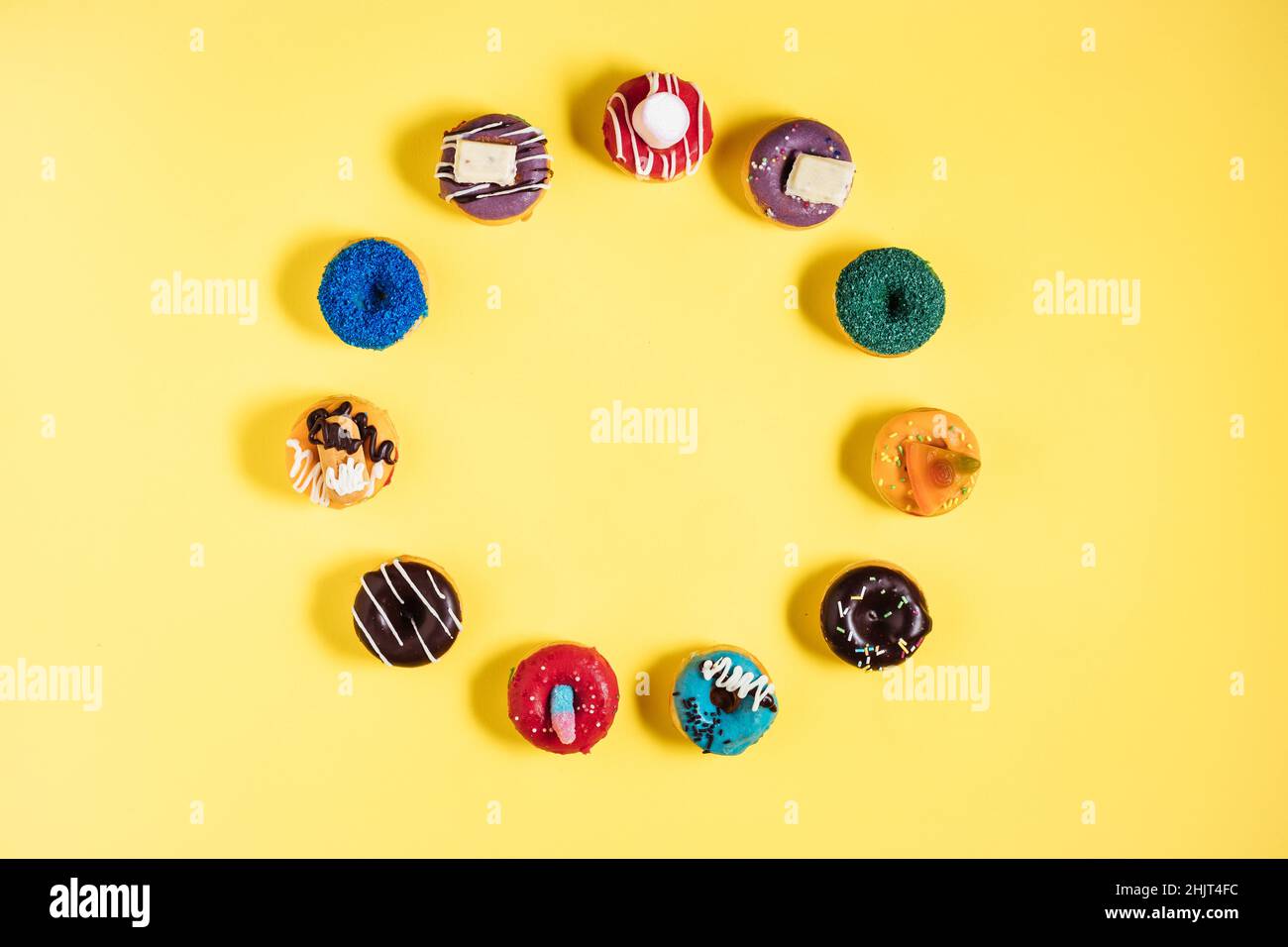 Bunte Donuts oder Donuts in verschiedenen Formen auf gelbem hellem Hintergrund. Farbenfrohes und glückliches Bild und Konzept. Stockfoto