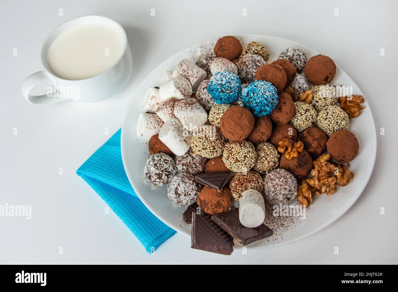 Trüffel mit Kakao, Kokosnuss und Sesam, Salmmielchen, einer Tasse frischer Milch Stockfoto
