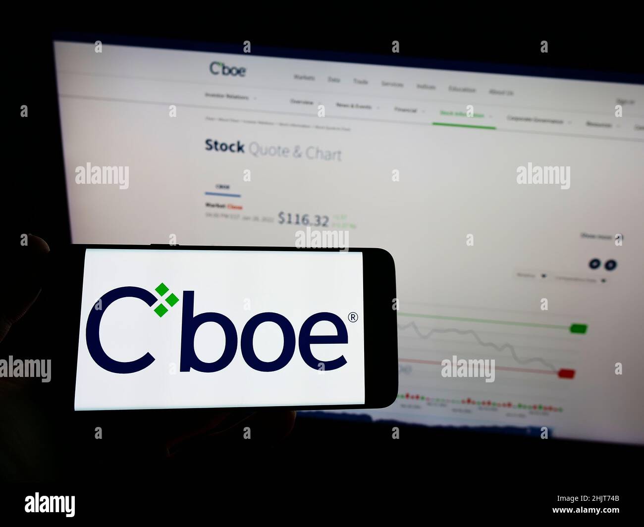 Person mit Mobiltelefon und Logo des US-Finanzunternehmens CBOE Global Markets Inc. Auf dem Bildschirm vor der Webseite. Konzentrieren Sie sich auf die Telefonanzeige. Stockfoto