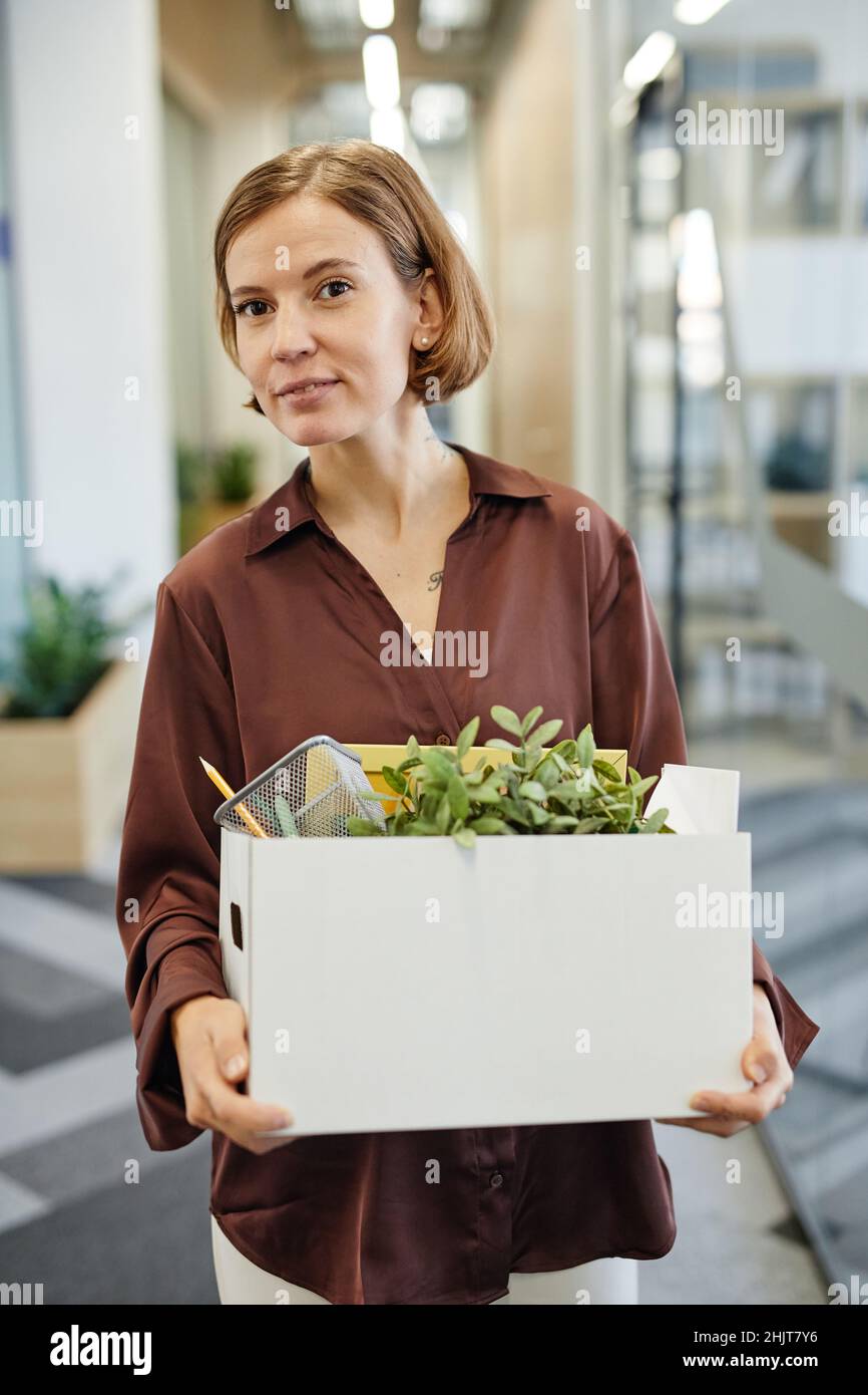 Vertikale Taille bis Porträt einer jungen Frau mit Box mit persönlichen Sachen beim Start neuer Job Stockfoto