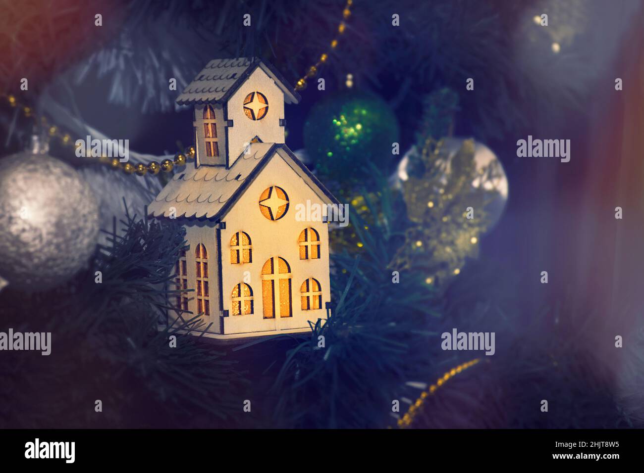 Retro-Holzhaus mit Licht aus den Fenstern, als Dekoration auf dem Weihnachtsbaum. Neujahrskarte Stockfoto