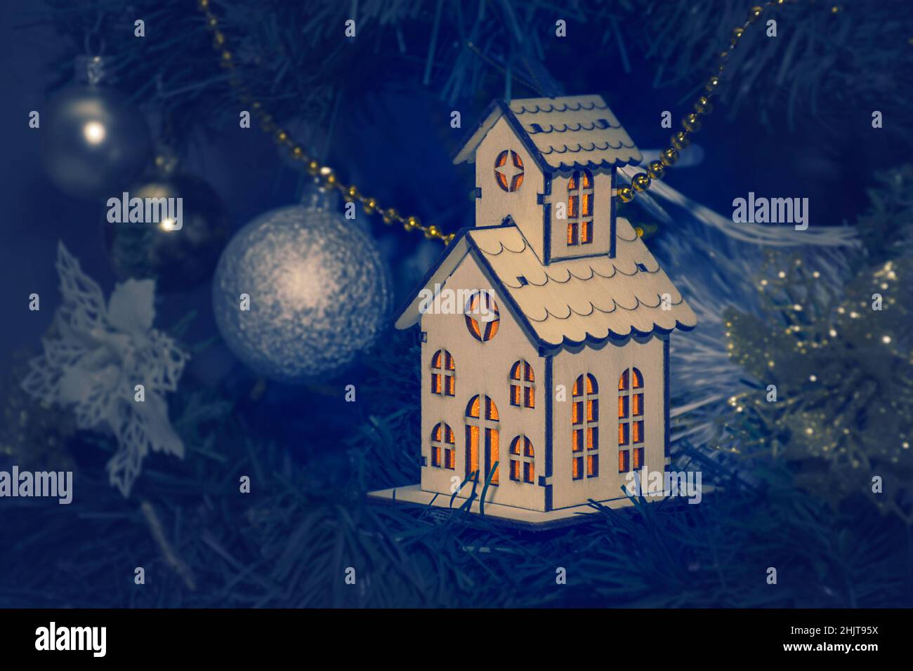 Retro-Holzhaus mit Licht aus den Fenstern, als Dekoration auf dem Weihnachtsbaum. Neujahrskarte Stockfoto