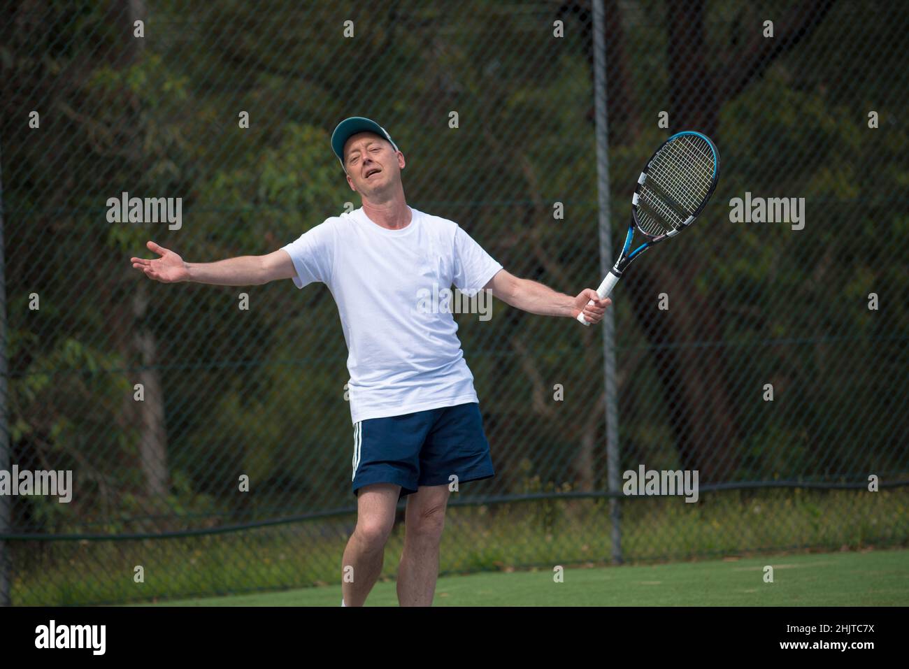 Ein Australier in den Fünfzigern oder Sechzigern steht auf einem örtlichen Tennisplatz, bewaffnet, und appelliert nach einer Entscheidung gegen ihn an den Schiedsrichter (Kamera) Stockfoto