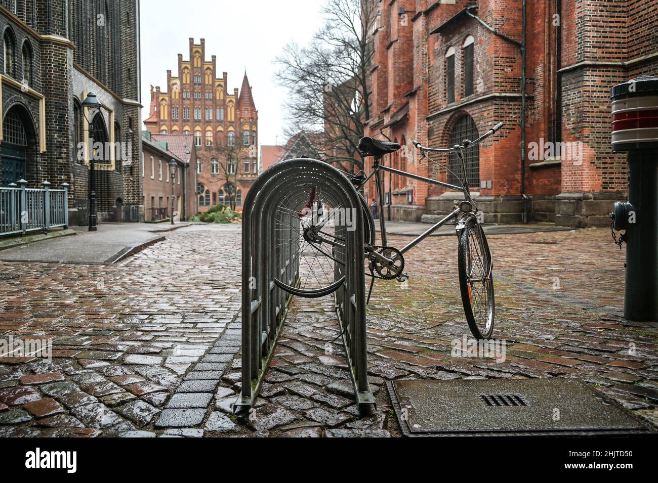 Radeln im Regen gesperrt auf dem öffentlichen Fahrradstand im Kirchhof der Marienkirche, Lübeck, Deutschland, Kopierraum, ausgewählter Fokus, Enge Tiefe Stockfoto