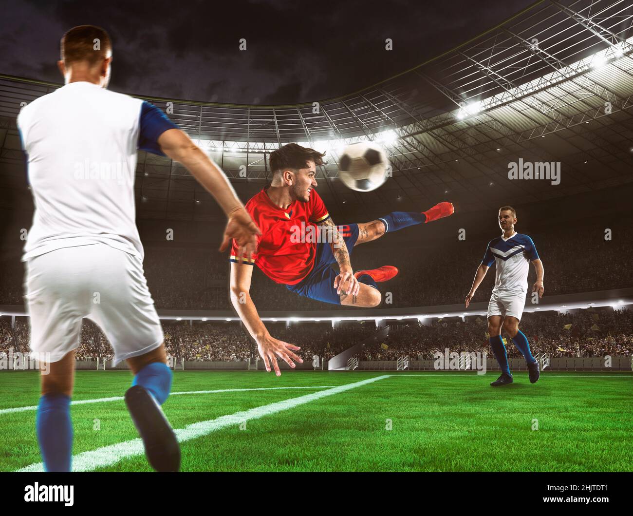 Fußballstürmer in rot-blauer Uniform trifft den Ball mit einem Kopfschuss in die Luft im Stadion Stockfoto