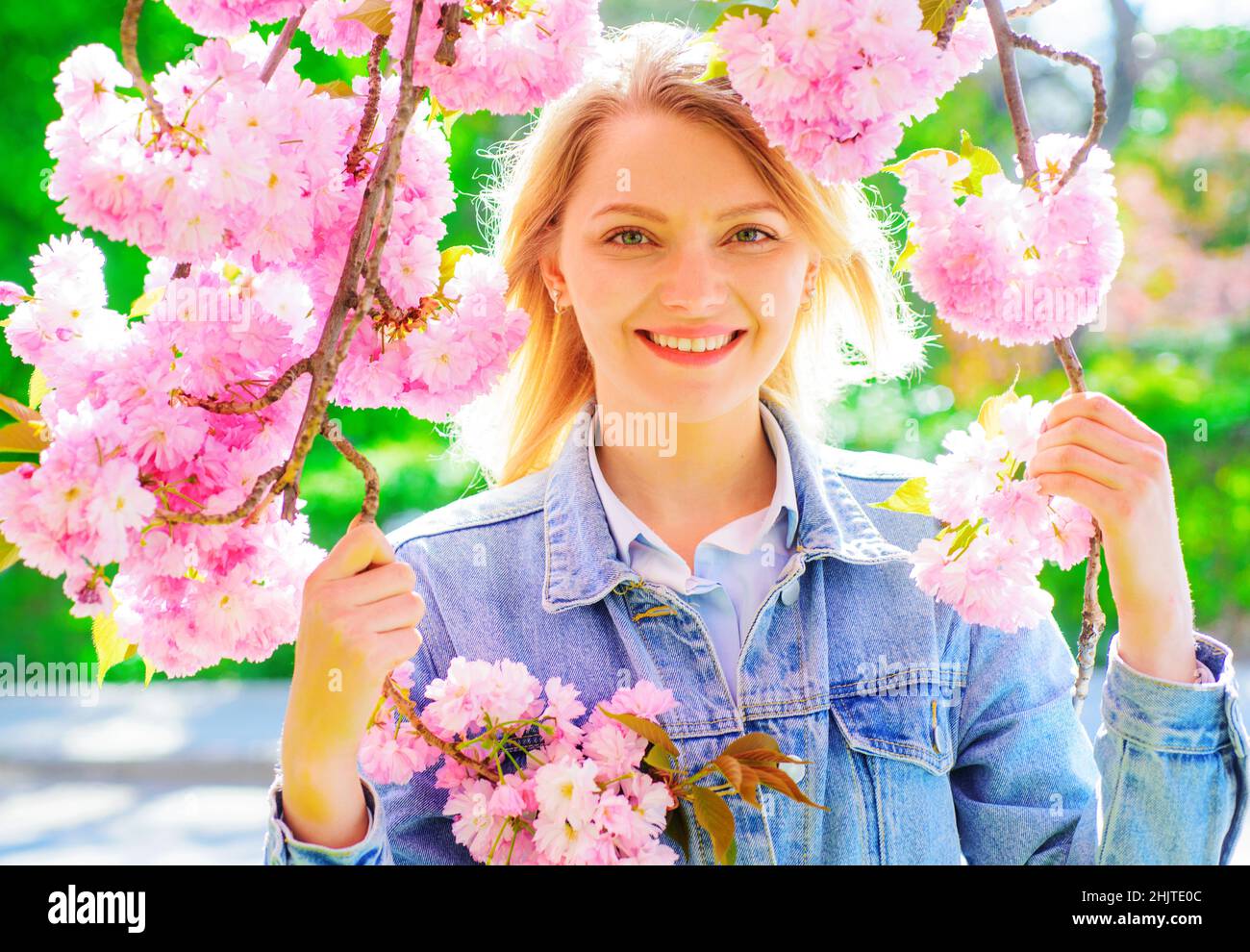 Lächelnde Frau im blühenden Sakura-Baum. Frühling. Schönes Mädchen genießen Frühling im Park an sonnigen Tag. Stockfoto